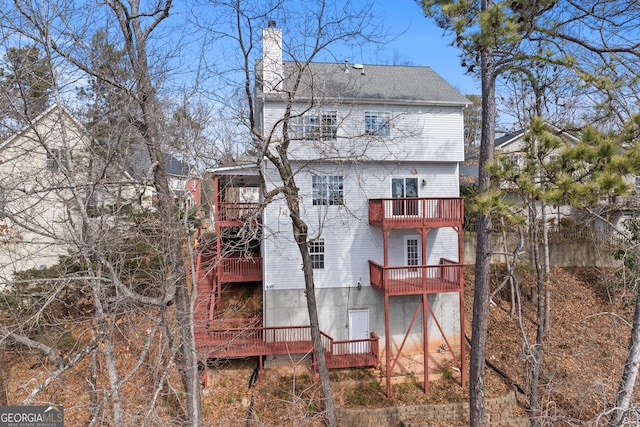 rear view of property with a balcony, a shingled roof, and a chimney