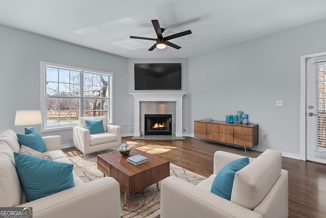 living room with a lit fireplace, wood finished floors, and baseboards