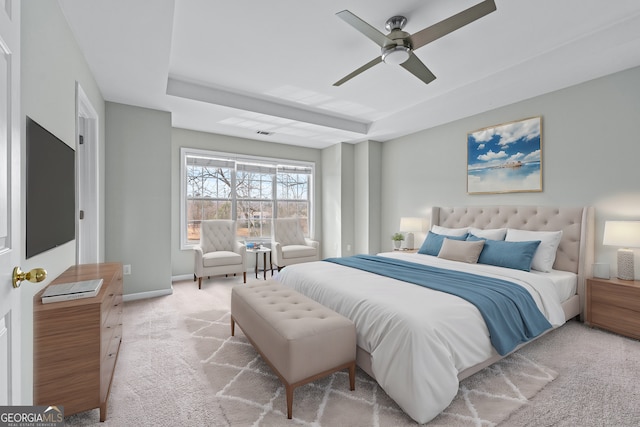 bedroom with a raised ceiling, visible vents, a ceiling fan, light carpet, and baseboards