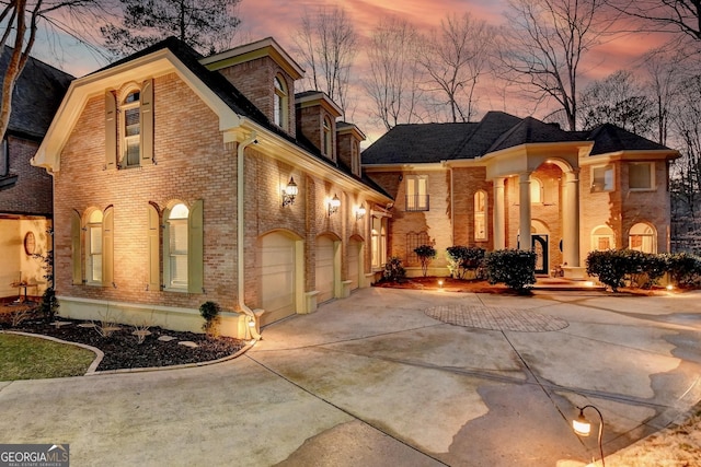 view of front of home with a garage, brick siding, and driveway