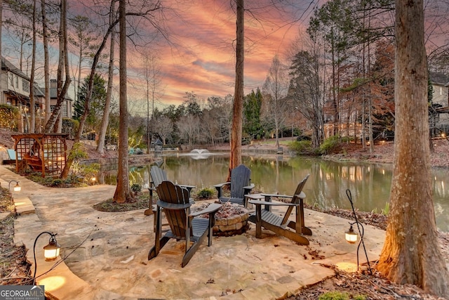 patio terrace at dusk with a water view and an outdoor fire pit