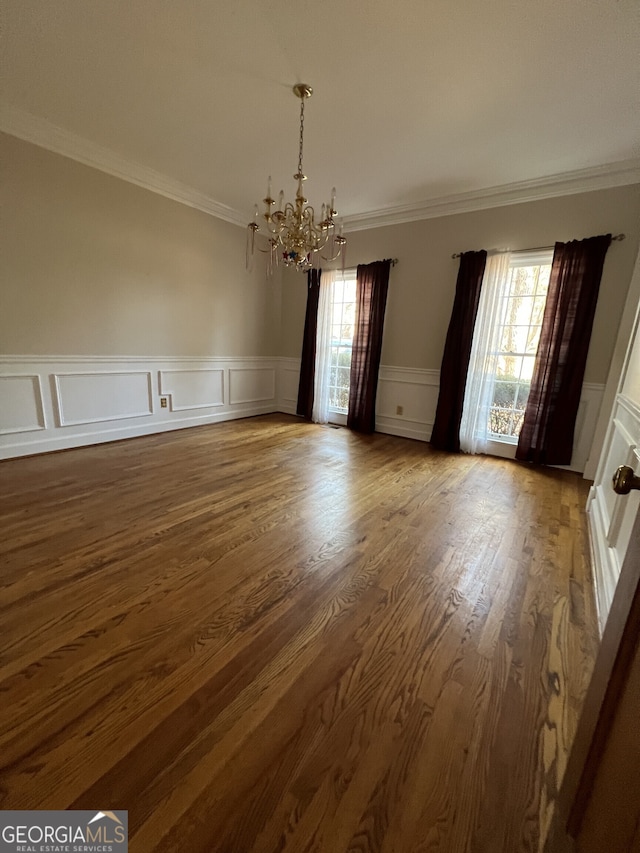 unfurnished dining area featuring a healthy amount of sunlight, a chandelier, wood finished floors, and ornamental molding