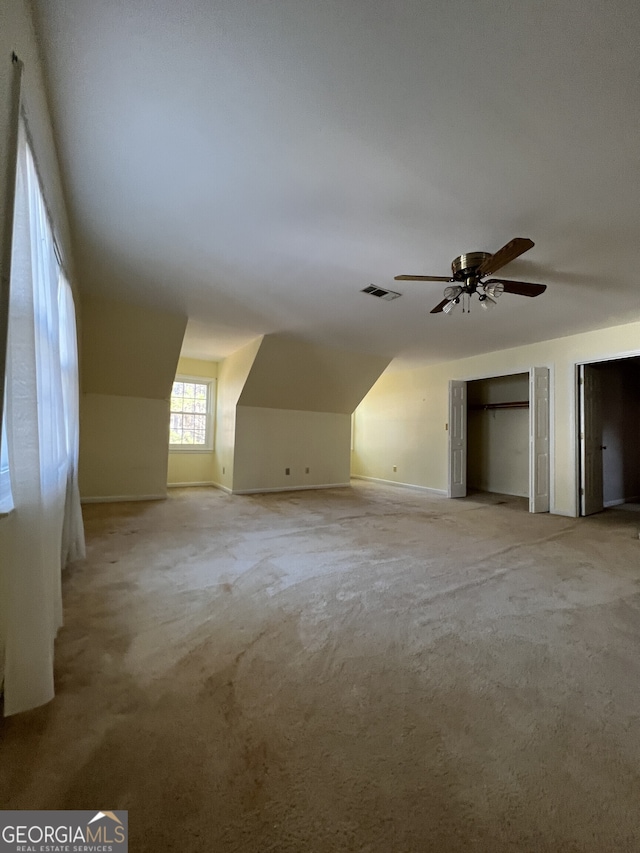 additional living space with baseboards, ceiling fan, visible vents, and light colored carpet