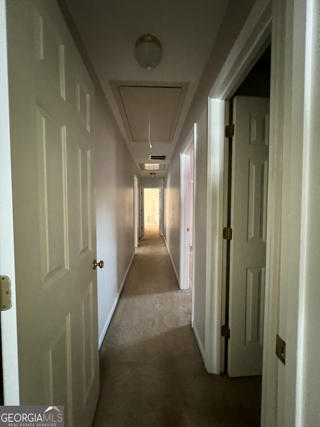 hall featuring carpet floors, attic access, and baseboards