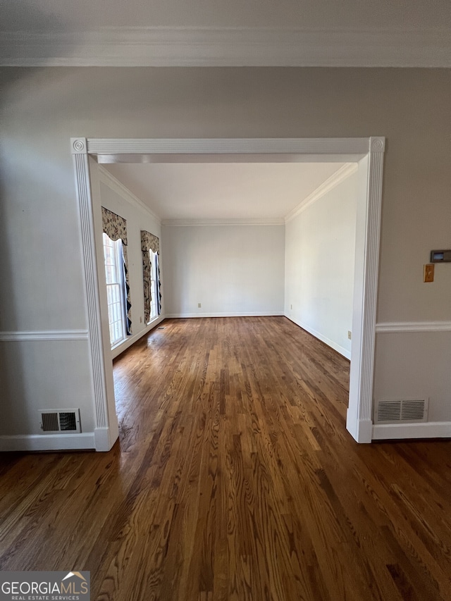 unfurnished living room featuring dark wood-type flooring, visible vents, and ornamental molding