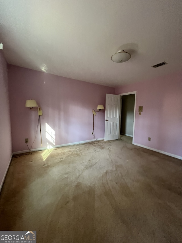 carpeted spare room featuring visible vents and baseboards