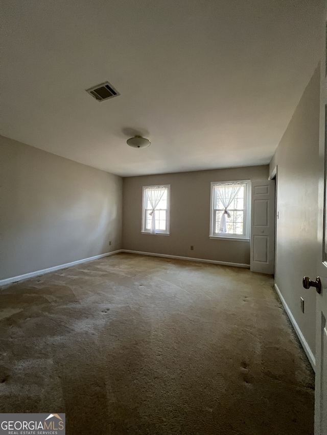 empty room featuring visible vents, baseboards, and light colored carpet