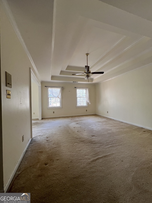 spare room with light carpet, baseboards, a tray ceiling, and ornamental molding