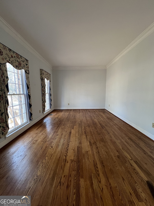 spare room featuring ornamental molding, baseboards, and wood finished floors