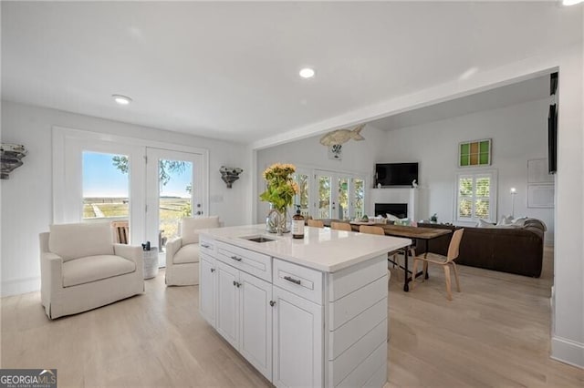 kitchen with a fireplace, white cabinets, open floor plan, light countertops, and a center island