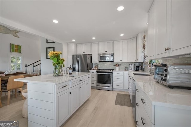 kitchen featuring a center island, backsplash, appliances with stainless steel finishes, white cabinetry, and a sink