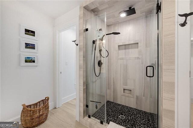 full bath with a stall shower, baseboards, and wood finished floors