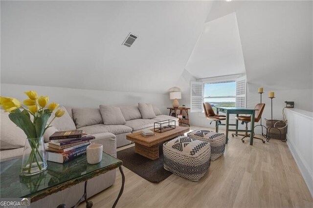 living room featuring lofted ceiling, visible vents, and light wood-style floors