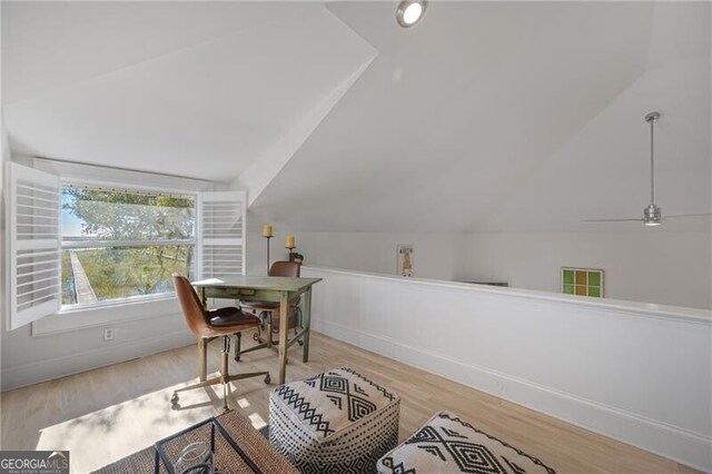 office space featuring light wood finished floors, baseboards, visible vents, and vaulted ceiling