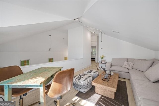 interior space featuring vaulted ceiling, light wood finished floors, visible vents, and attic access