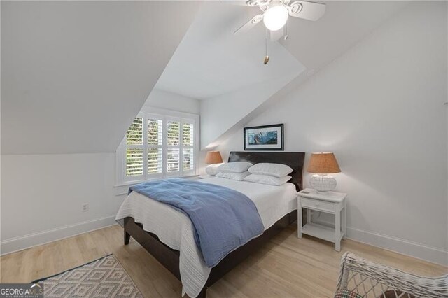 bedroom featuring baseboards, vaulted ceiling, light wood finished floors, and ceiling fan