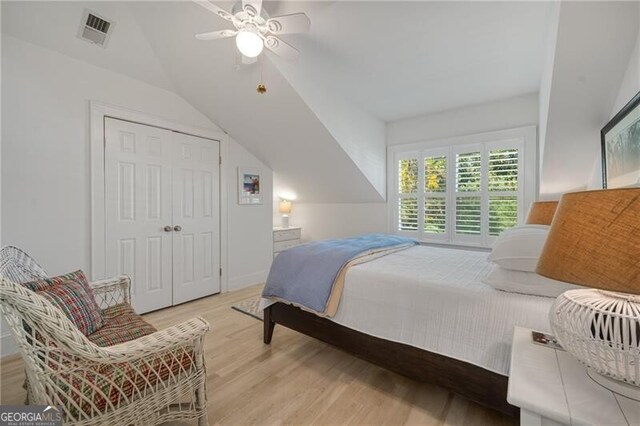 bedroom with lofted ceiling, a closet, visible vents, light wood-style floors, and ceiling fan