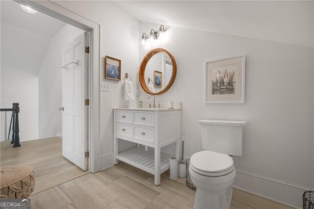 bathroom featuring toilet, vaulted ceiling, and vanity