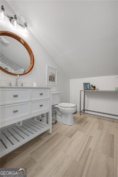 bathroom featuring lofted ceiling, vanity, and toilet