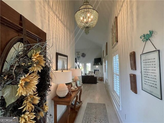 hallway featuring a chandelier, a high ceiling, and wood finished floors