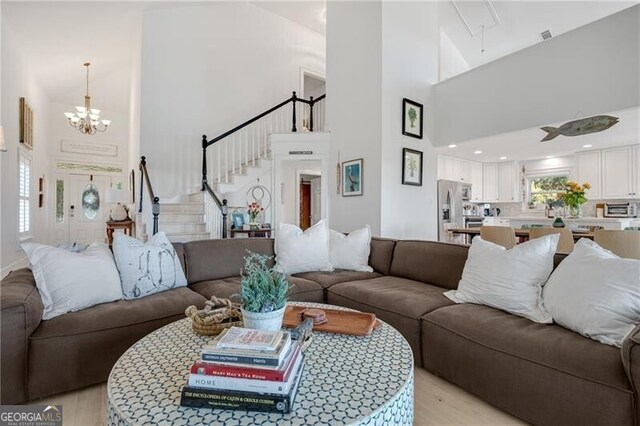 living area featuring stairs, a high ceiling, and a chandelier