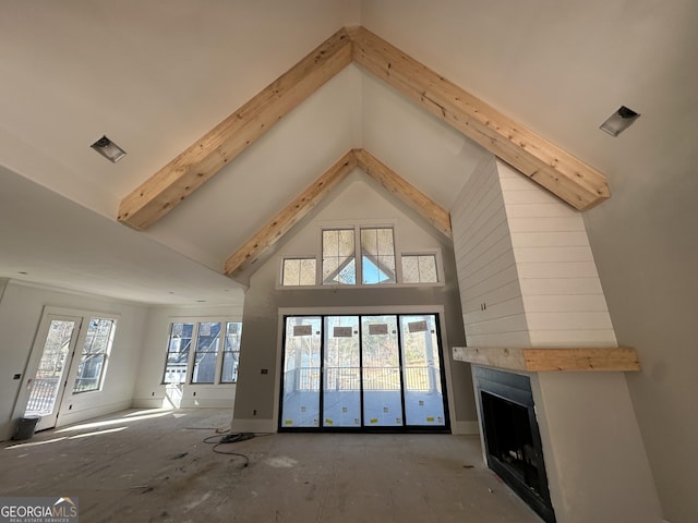 unfurnished living room featuring a healthy amount of sunlight, a fireplace, high vaulted ceiling, and beam ceiling