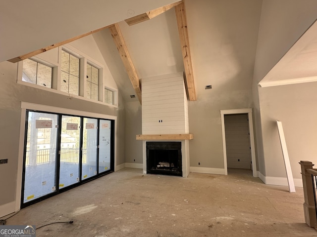 unfurnished living room with a large fireplace, a towering ceiling, and baseboards