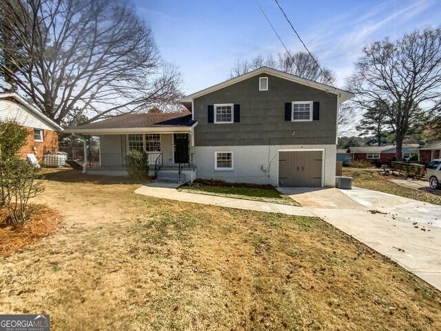 view of front facade with driveway, a garage, covered porch, cooling unit, and a front yard