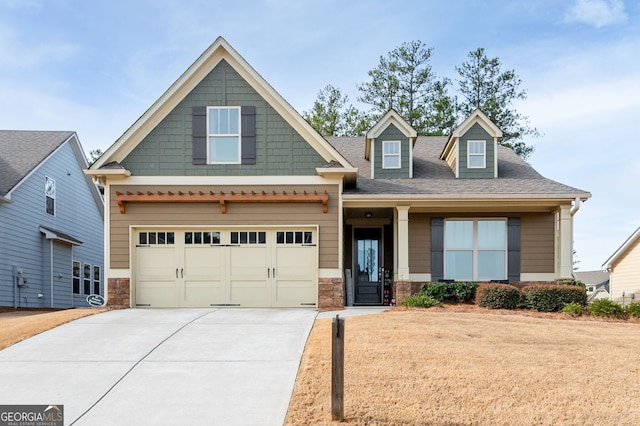 craftsman-style house with a shingled roof, stone siding, and concrete driveway