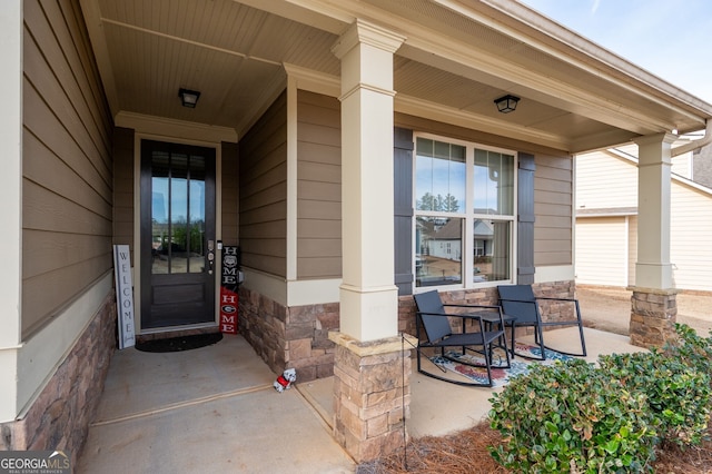 property entrance with stone siding and a porch