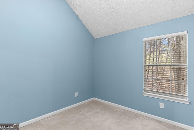 carpeted empty room with baseboards, vaulted ceiling, and a textured ceiling