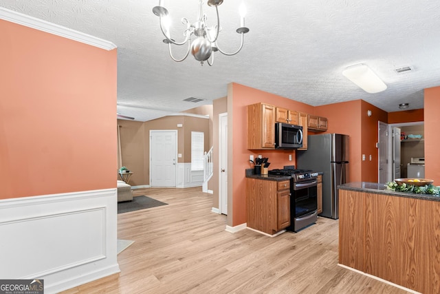 kitchen with pendant lighting, dark countertops, visible vents, light wood-style flooring, and appliances with stainless steel finishes