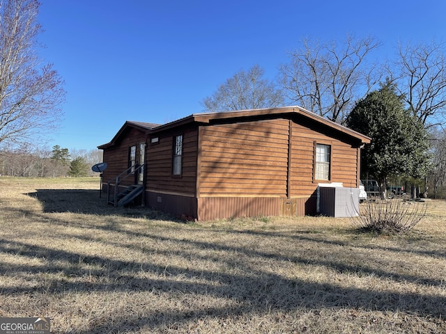 view of home's exterior with entry steps, cooling unit, and a yard