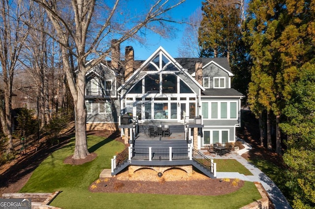 rear view of house featuring a chimney, a yard, and a deck