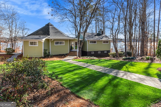 back of house with crawl space, roof with shingles, and a lawn