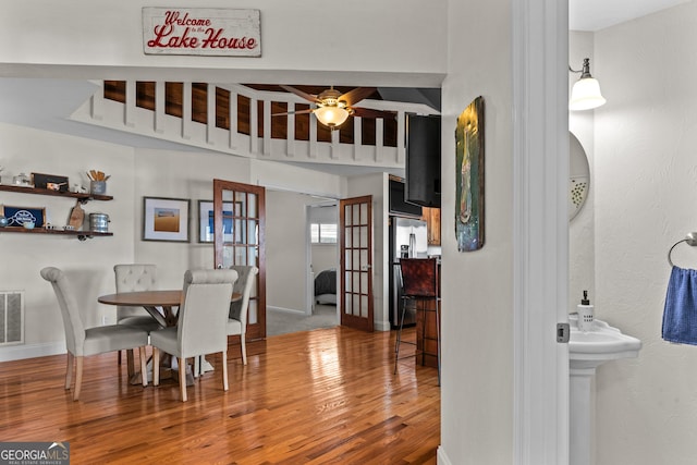 dining space with baseboards, visible vents, wood finished floors, and a ceiling fan