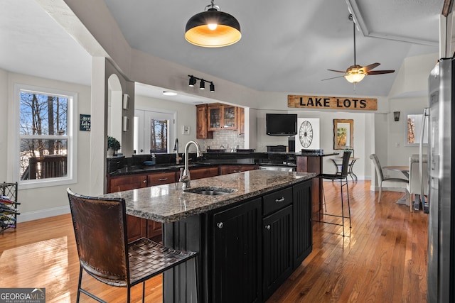 kitchen featuring light wood-type flooring, a kitchen breakfast bar, a sink, and freestanding refrigerator