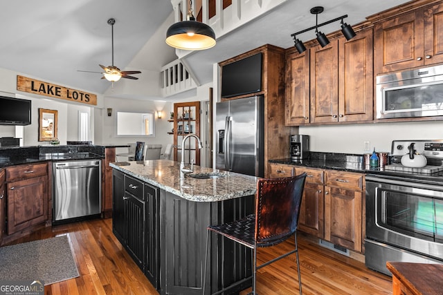kitchen featuring wood finished floors, stainless steel appliances, a ceiling fan, an island with sink, and a sink