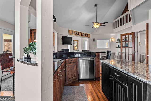 kitchen with open floor plan, vaulted ceiling, dark wood finished floors, dark stone counters, and a ceiling fan