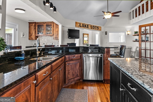 kitchen featuring ceiling fan, wood finished floors, dark stone countertops, a sink, and vaulted ceiling