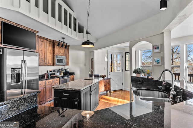 kitchen with brown cabinetry, light wood-style flooring, a sink, and stainless steel appliances