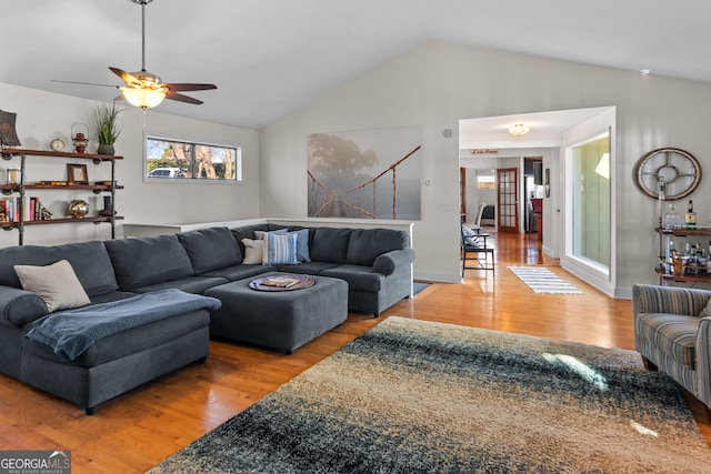 living area with baseboards, vaulted ceiling, wood finished floors, and a ceiling fan