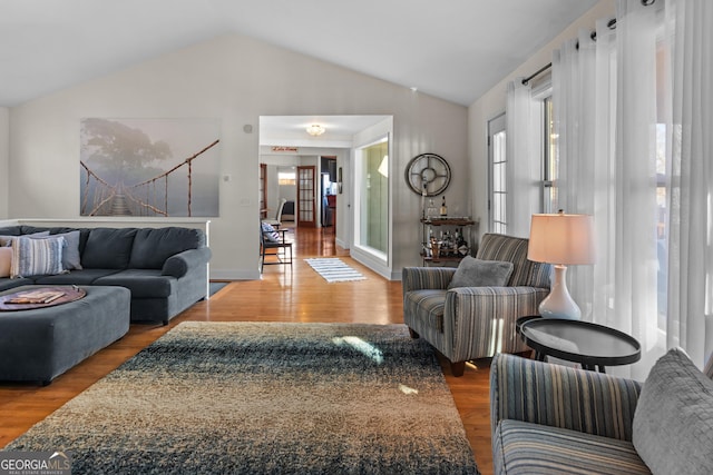 living room with baseboards, lofted ceiling, and wood finished floors