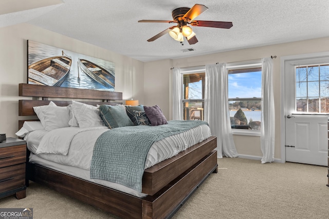 bedroom with light colored carpet, visible vents, baseboards, and a textured ceiling