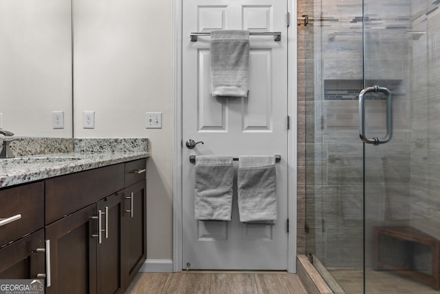 bathroom featuring vanity, a stall shower, and wood finished floors