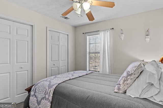 bedroom with visible vents, multiple closets, and a ceiling fan