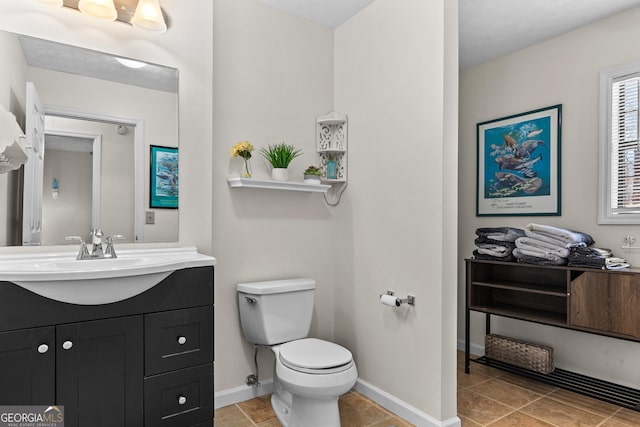bathroom featuring baseboards, toilet, and vanity