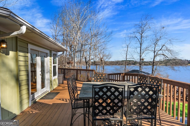 wooden terrace with french doors, outdoor dining area, and a water view