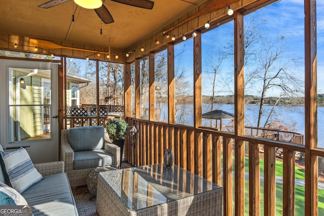unfurnished sunroom featuring a water view, outdoor lounge area, and ceiling fan