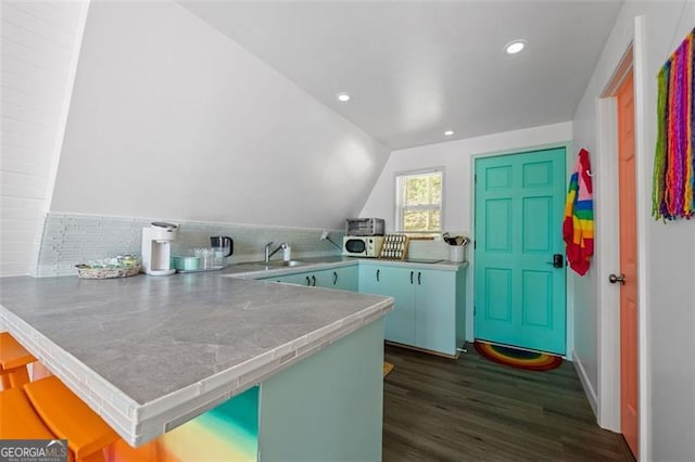 kitchen with a peninsula, vaulted ceiling, dark wood-style flooring, and recessed lighting